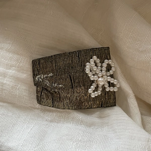 Detail of vintage gold fabric hair clip with a bow made of white faux pearls