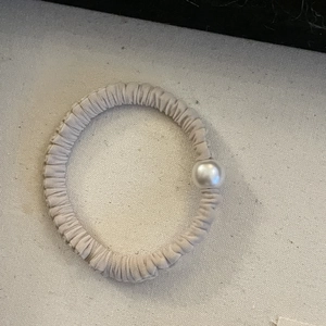 Elastico per capelli crema minimalista con una grande perla su sfondo in tessuto
