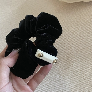 Macro shot of black velvet scrunchie with a rectangle bead and gold accents