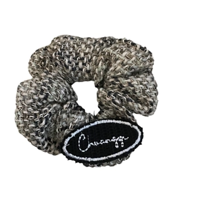 Chic tweed scrunchie in grey and beige tones with a stylish embroidered logo tag