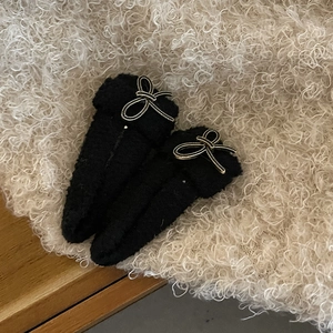 Lot de deux barrettes en polaire noire avec nœuds dorés sur fond de textile chaud