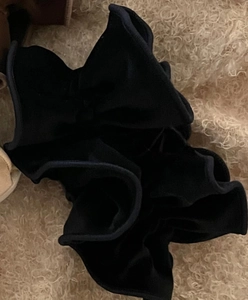 Dettaglio di elastico per capelli in velluto nero con texture morbida e design a pieghe
