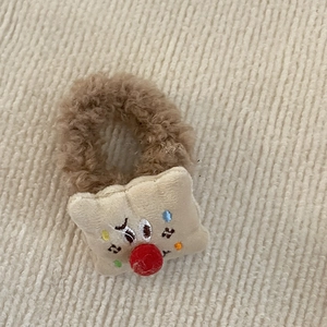 Detail eines flauschigen braunen Teddybär-Haargummis mit weichen Stickereien und Textur