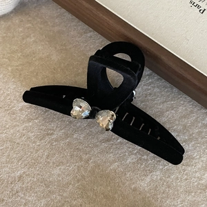 Detail of black velvet hair claw clip with heart-shaped crystals and matte texture