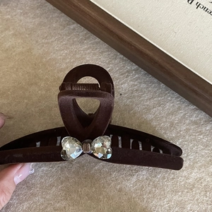 Elegant dark brown velvet hair claw clip with heart crystal bow detail on beige background