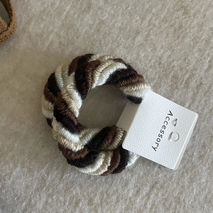 Thick braided elastic hair ties in brown and beige tones on an accessory card