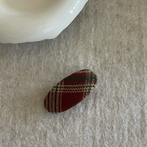 Close-up of a vintage British style plaid BB hair clip on a textured grey surface