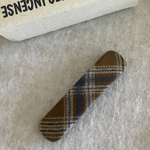 Macro shot of a rectangular plaid hair clip with deep brown and blue fabric texture