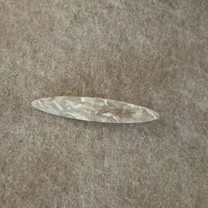 Elegant marble acetate hair clip with handmade engraving on minimalist beige felt background