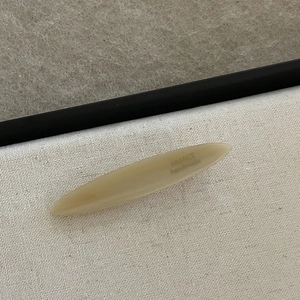 Handmade acetate beige hair clip with France engraving on elegant neutral canvas background