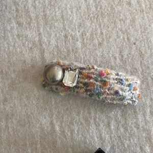 Detailed close-up of a colorful knitted hair clip with grey pearl and crystal stone decor