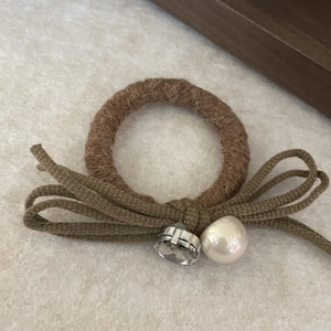 Chouchou en peluche marron avec nœud vert, perle blanche et accents de cristal