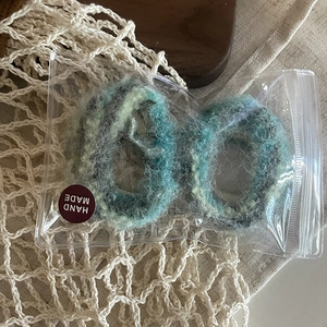 Gros plan de deux chouchous en mohair faits main en fil de laine bleu-gris dégradé