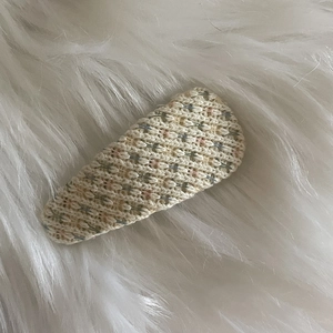 Gros plan sur une pince à cheveux en tricot beige avec des fils colorés sur fourrure