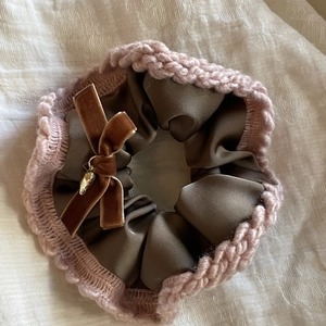 Brown satin scrunchie with pink knit trim and velvet bow on textured fabric