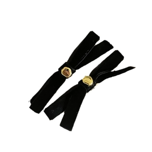 Pair of black velvet bow hair clips with gold geometric metal buckles on white background