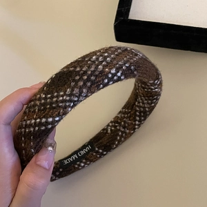 Close-up of handmade label on brown plaid sponge headband with thick knit texture