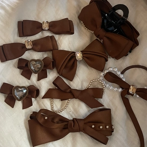 Ensemble de 8 accessoires cheveux marrons avec nœuds, perles et strass sur tissu blanc