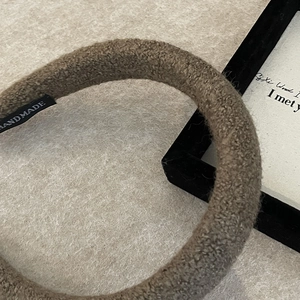 Detailed close-up of dark brown plush sponge headband with handmade woven tag