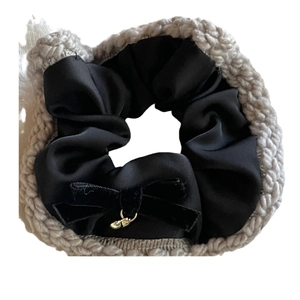 Knitted grey hair scrunchie with a velvet bow and small golden bell on white background