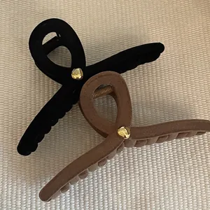Large black and brown velvet hair claws with gold button details on beige texture