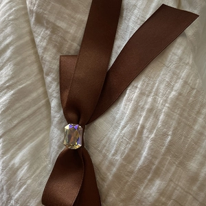 Barrette à cheveux nœud en satin marron avec cristal rectangulaire sur tissu blanc