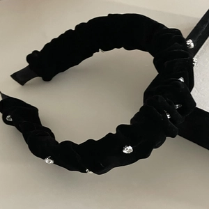 Detailed close-up of a black velvet pleated headband with shiny silver rhinestones