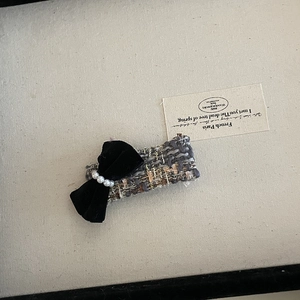 Close-up of French tweed hair claw with black velvet bow and faux pearls decoration