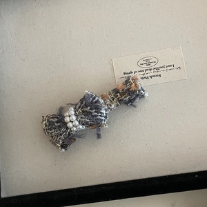 Detail of tweed bow hair claw clip with woven blue yarn and elegant white pearls