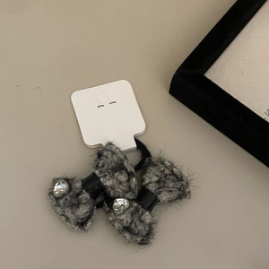 Detail of plush grey bow hair ties with sparkling rhinestone centers on a display card