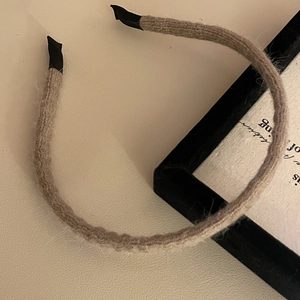 Detailed macro view of light brown knitted headband with soft texture on leather surface