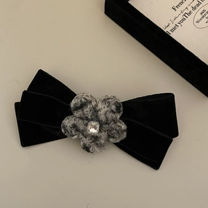 Detail of black velvet bow hair clip with tweed flower and crystal center