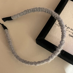 Macro view of grey knitted pleated headband with textured wavy design and anti-slip ends