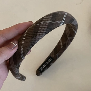 Detail of hand-made brown plaid fabric headband featuring a black hand-made woven label