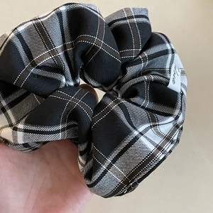 Macro detail of large brown plaid scrunchie with logo tag showing fabric texture