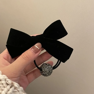 Elegant velvet bow hair scrunchie with crystal ball decoration held against a sweater