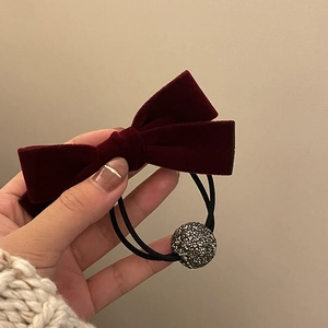 Detail of burgundy velvet bow hair tie featuring a sparkling diamond ball pendant