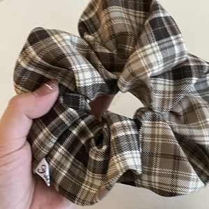 Close-up of brown plaid scrunchie with soft fabric texture and a small white brand label