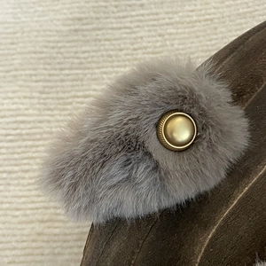 Elegant grey plush hair clip with vintage gold button accessory on wooden background