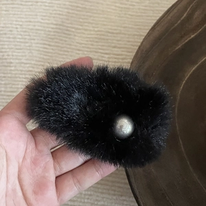 Close-up of soft black plush hair clip with a stylish silver grey pearl embellishment