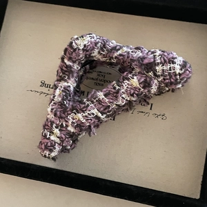 Macro detail of purple and white tweed fabric hair claw clip with golden threads