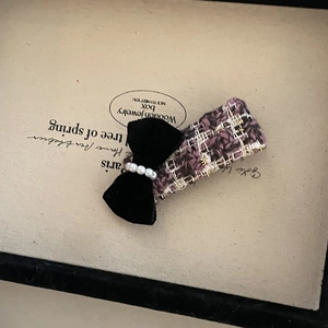 Macro detail of grape purple tweed hair claw with black velvet bow and white pearls