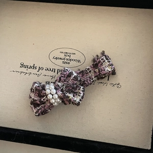 Close-up of purple tweed bow hair claw clip with elegant faux pearl embellishments