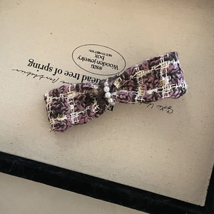 Detail of tweed bow hair claw with purple weave and elegant pearl embellishments