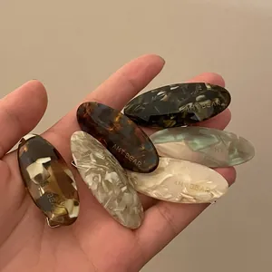 Set of 5 acetate hair clips in tortoiseshell and marble patterns held in hand