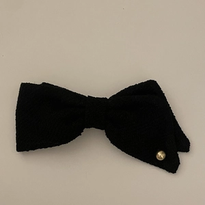 Close-up of black tweed fabric bow clip featuring a polished gold metal stud detail