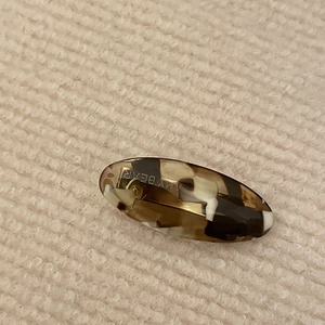 Vintage tortoiseshell acetate hair clip with gold metal spring on a knit background