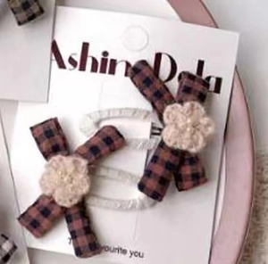 Close-up of red and black plaid hair clips with crochet flowers and pearls on card