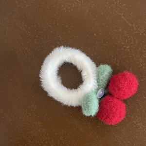 Close-up of cute white plush cherry hair scrunchie with red cherries and green felt leaves