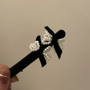 Elegant velvet bow hair clip featuring white imitation pearls on a warm background